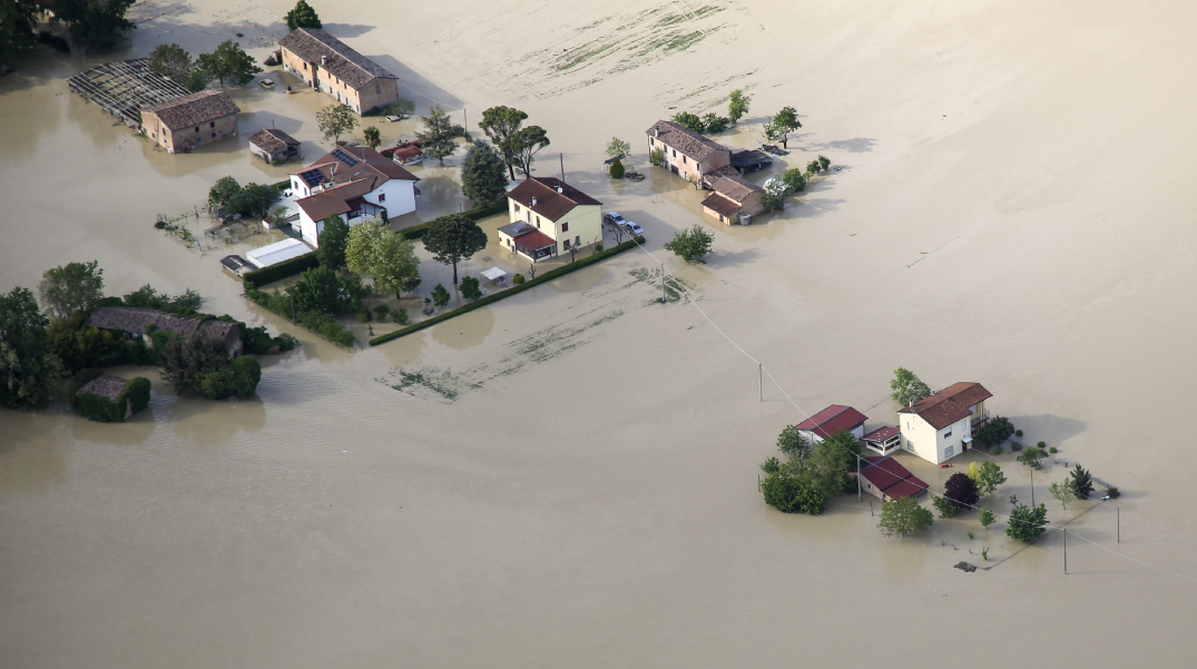 Veduta aerea di case e cascine circondate da acque di piena con campi e strade completamente allagati durante l'alluvione del 2023