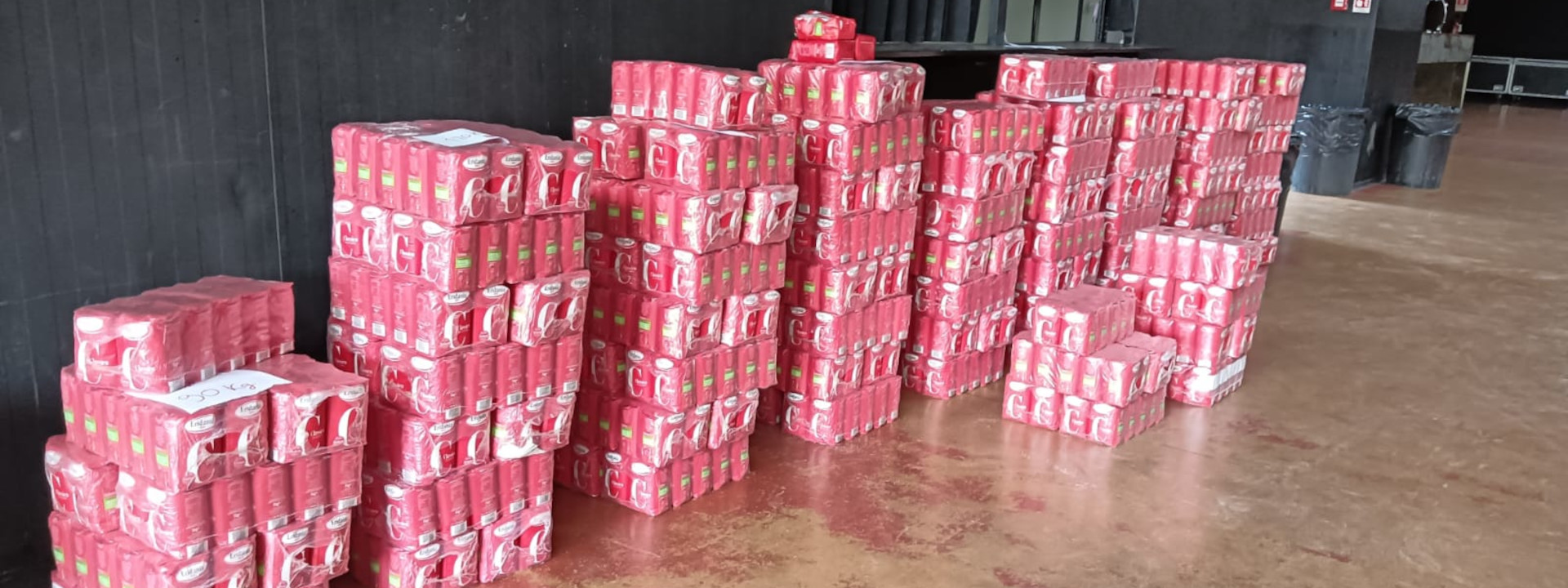 Torri di confezioni rosse di zucchero Eridania impilate su un pavimento lucido con parete nera sullo sfondo