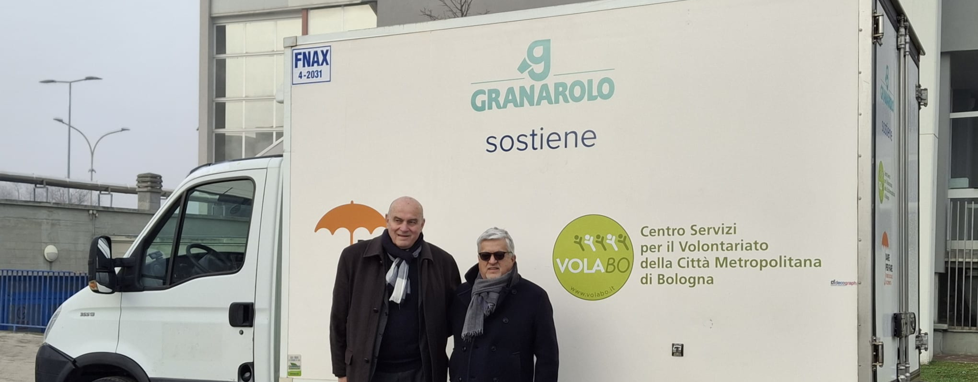 Due persone posano davanti a un furgone refrigerato con il logo Granarolo e Volabo, utilizzato per la donazione di prodotti freschi alla comunità