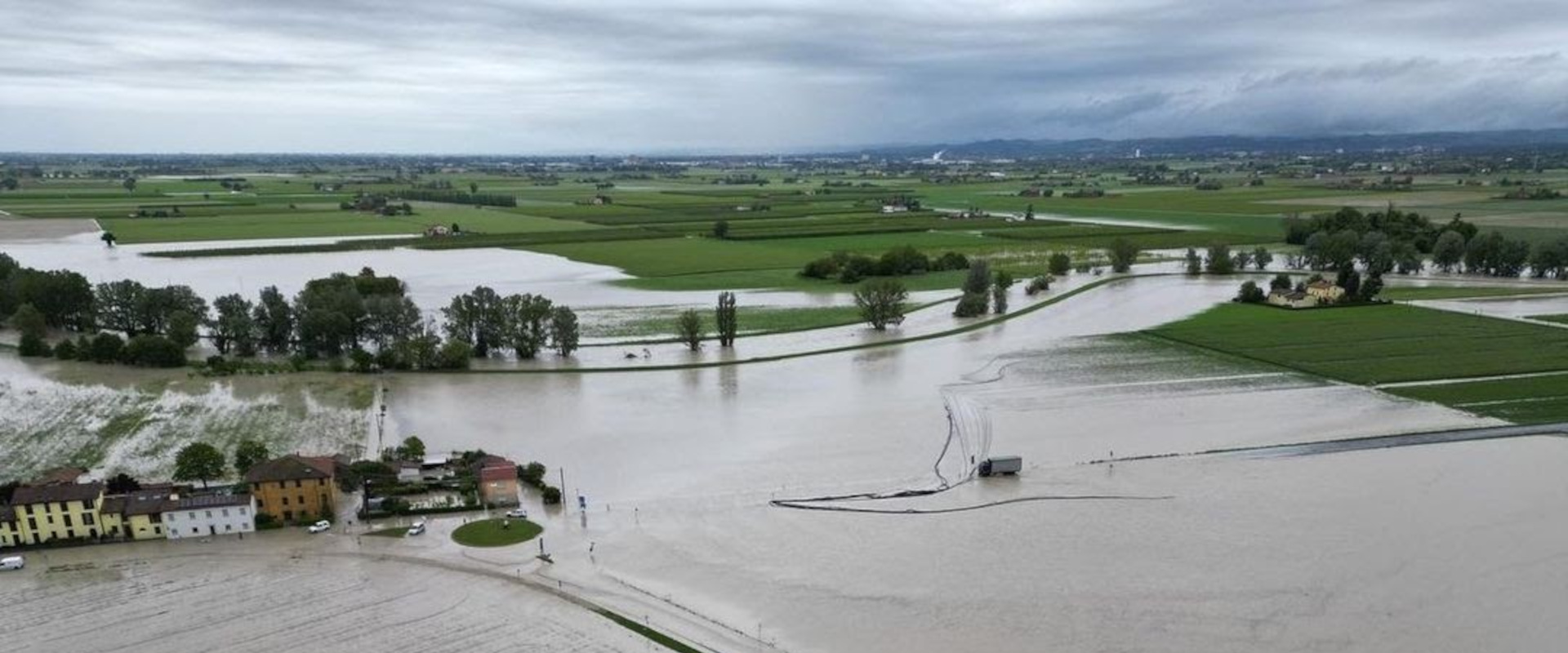 Veduta aerea di campi e strade sommerse dall'acqua durante un'alluvione con alcune case e alberi circondati dall'esondazione